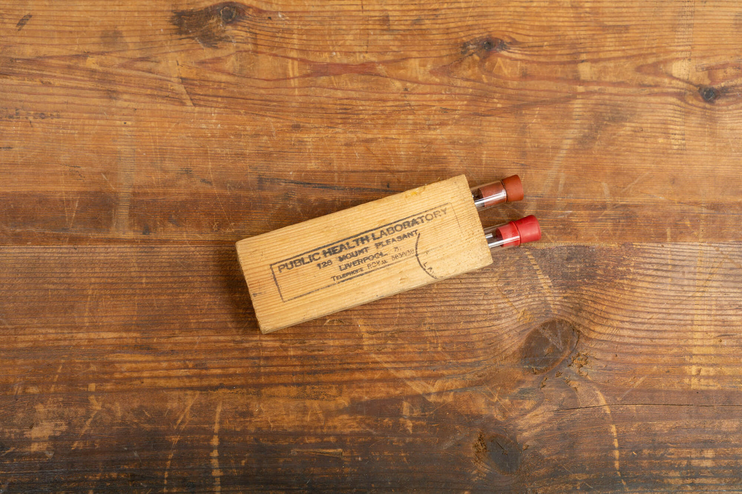 A flatlay photo taken from above of two vintage test tubes in a wooden holder.