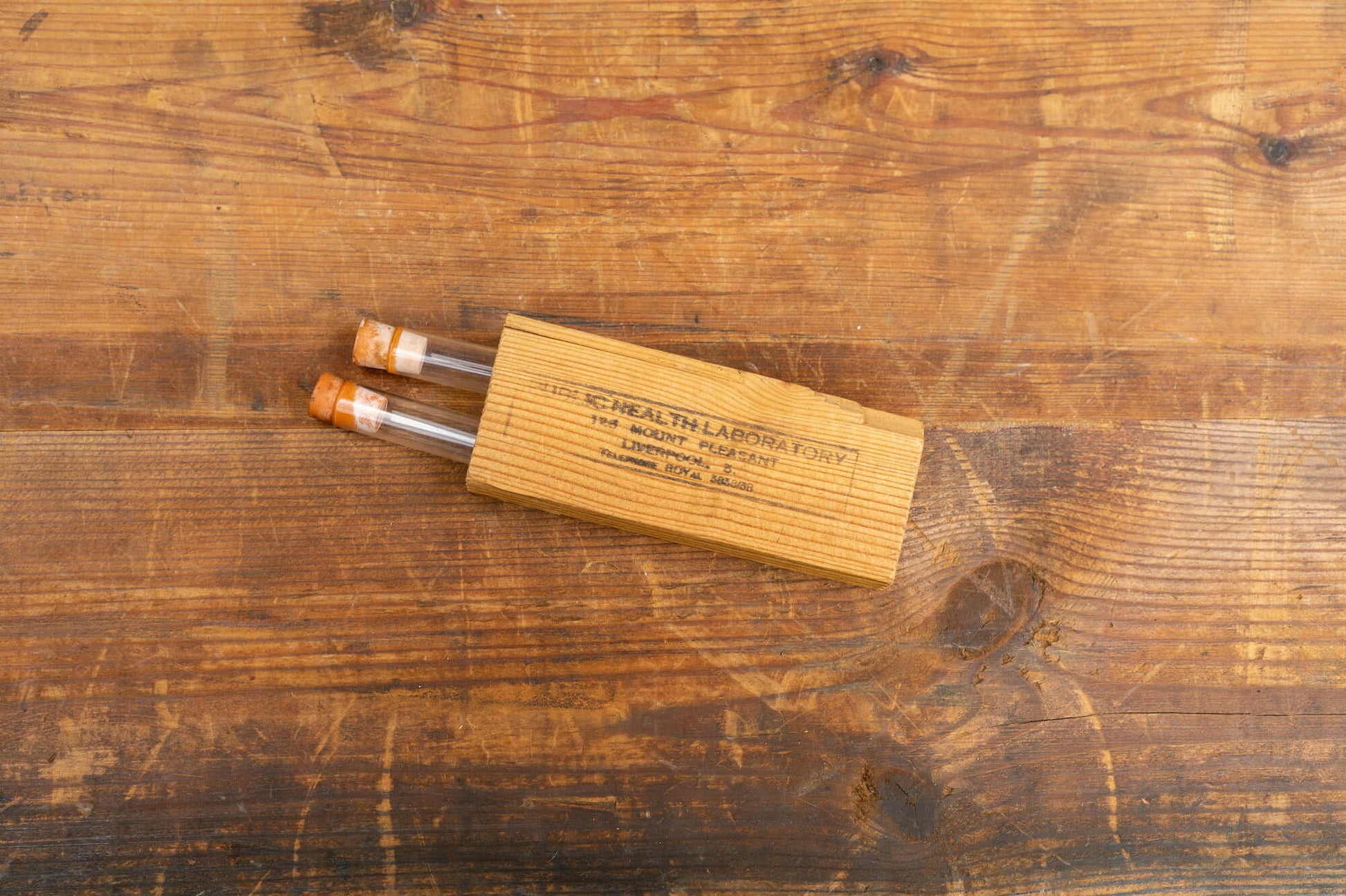 A flatlay photo taken from above of two vintage test tubes in a wooden holder.