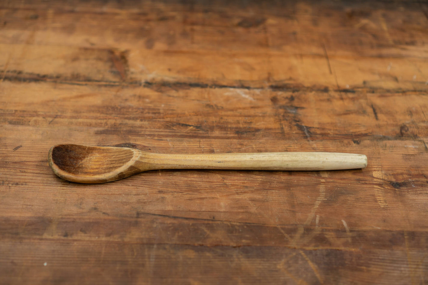 vintage wooden spoons for the victorian farmhouse style kitchen. Three spoons atop a wooden table with a blurred brick wall in the background.