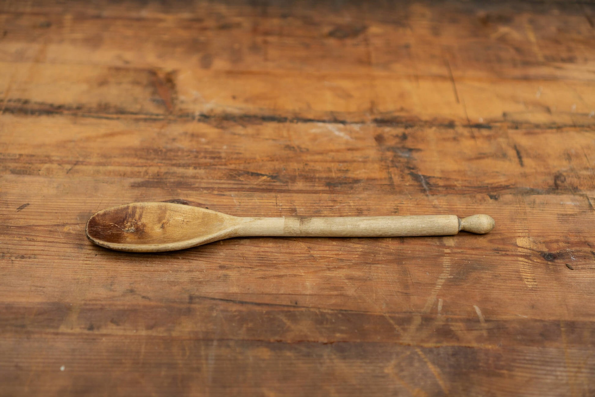 vintage wooden spoons for the victorian farmhouse style kitchen. Three spoons atop a wooden table with a blurred brick wall in the background.