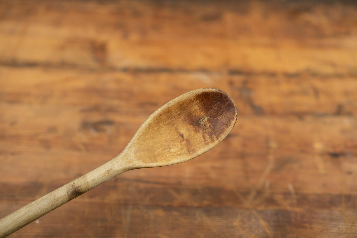 vintage wooden spoons for the victorian farmhouse style kitchen. Three spoons atop a wooden table with a blurred brick wall in the background.