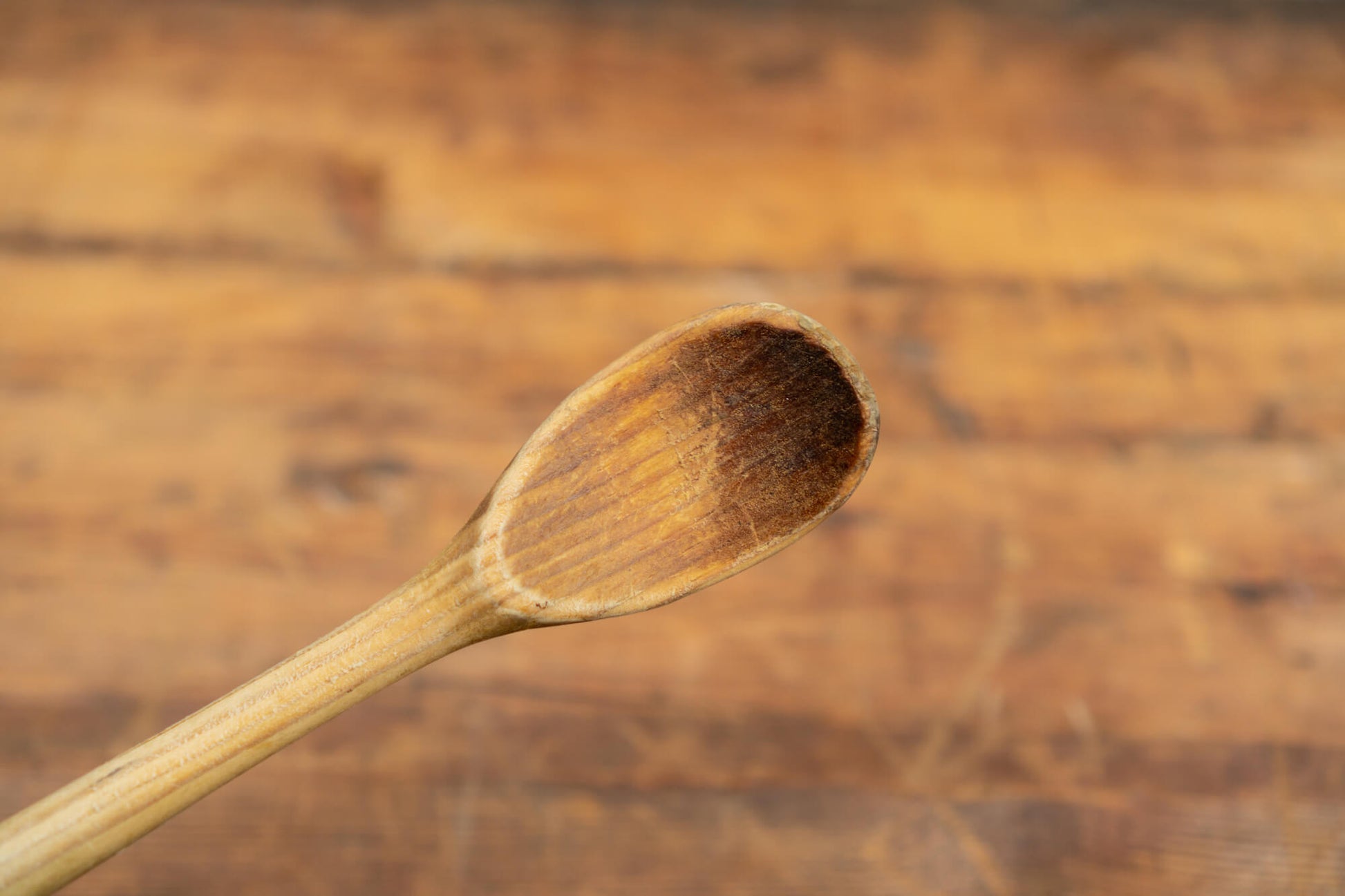 vintage wooden spoons for the victorian farmhouse style kitchen. Three spoons atop a wooden table with a blurred brick wall in the background.