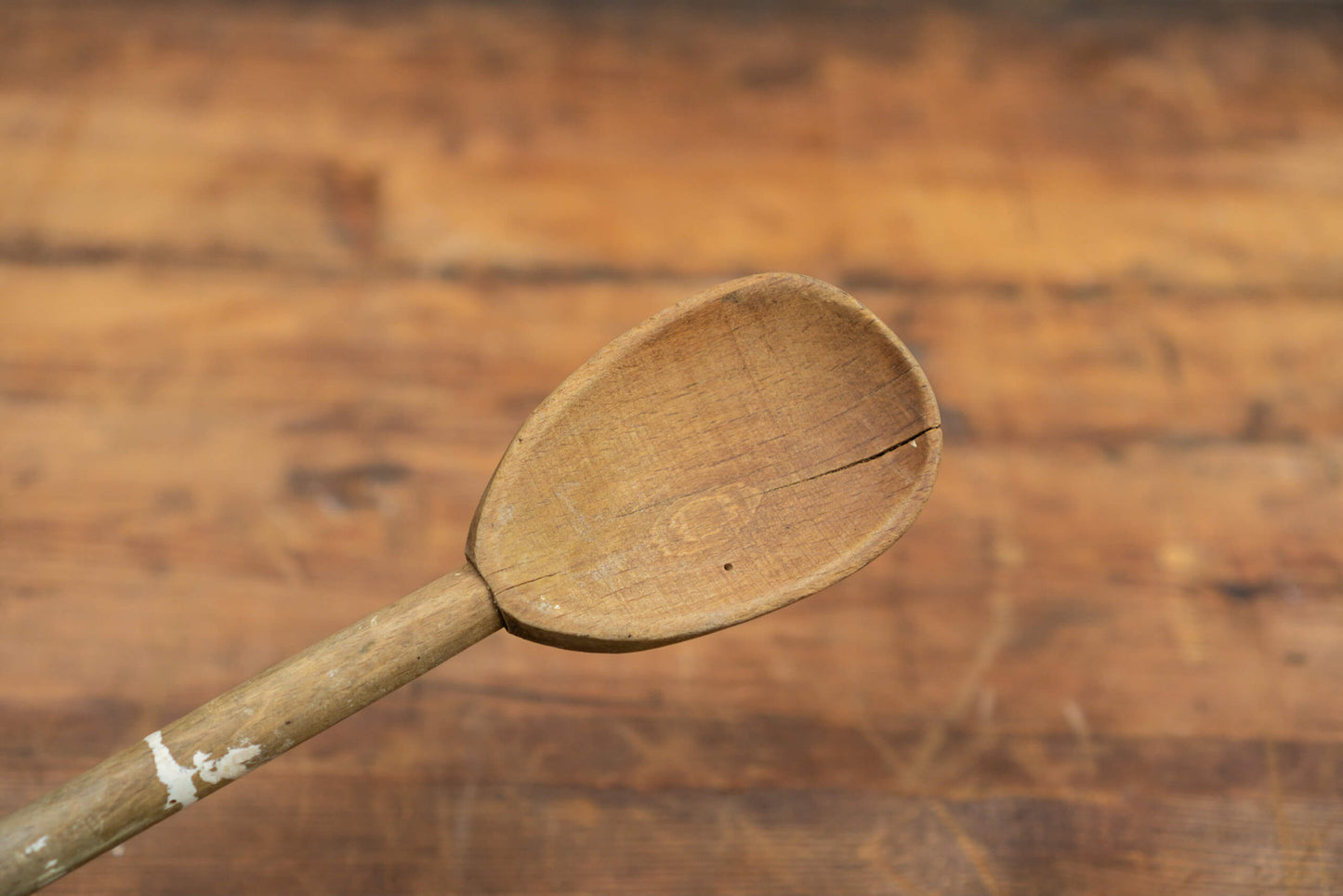 vintage wooden spoons for the victorian farmhouse style kitchen. Three spoons atop a wooden table with a blurred brick wall in the background.