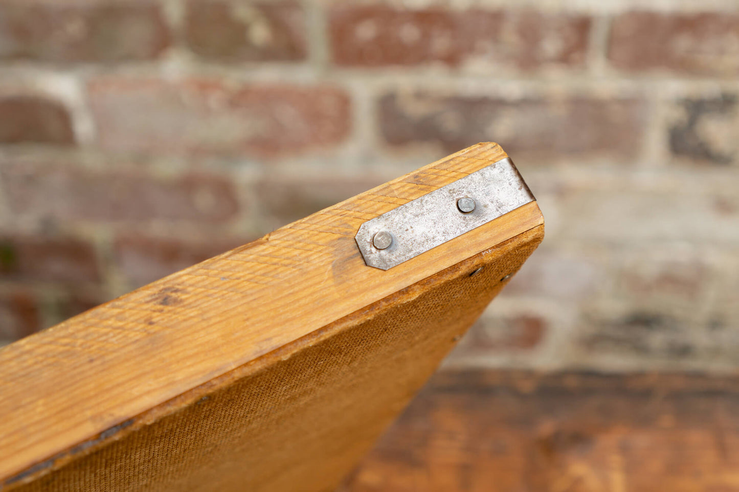 Photo shows a vintage selection of wooden seed trays atop a table. The background is a red rustic brick wall.