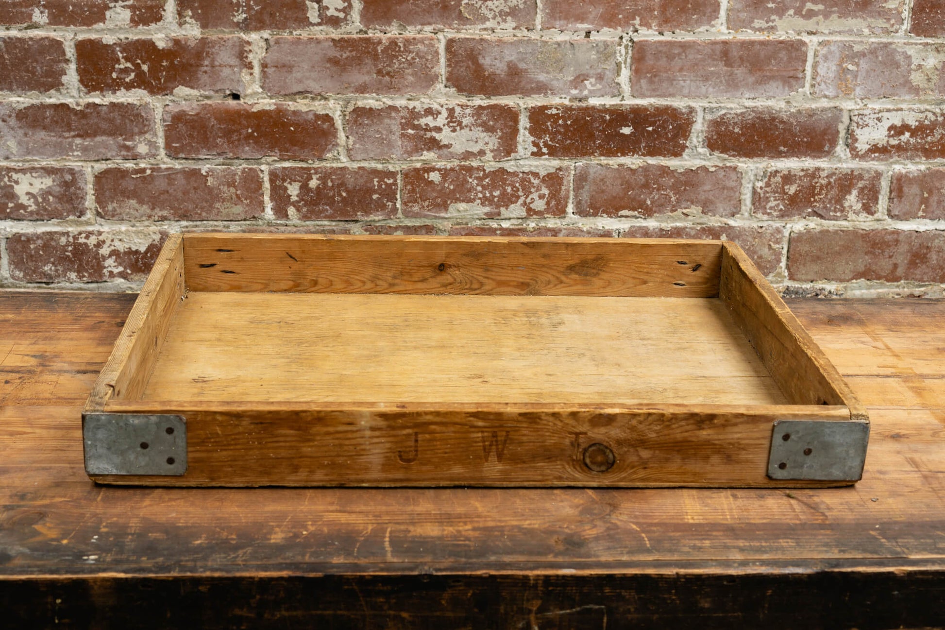 Photo shows a vintage selection of wooden seed trays atop a table. The background is a red rustic brick wall.