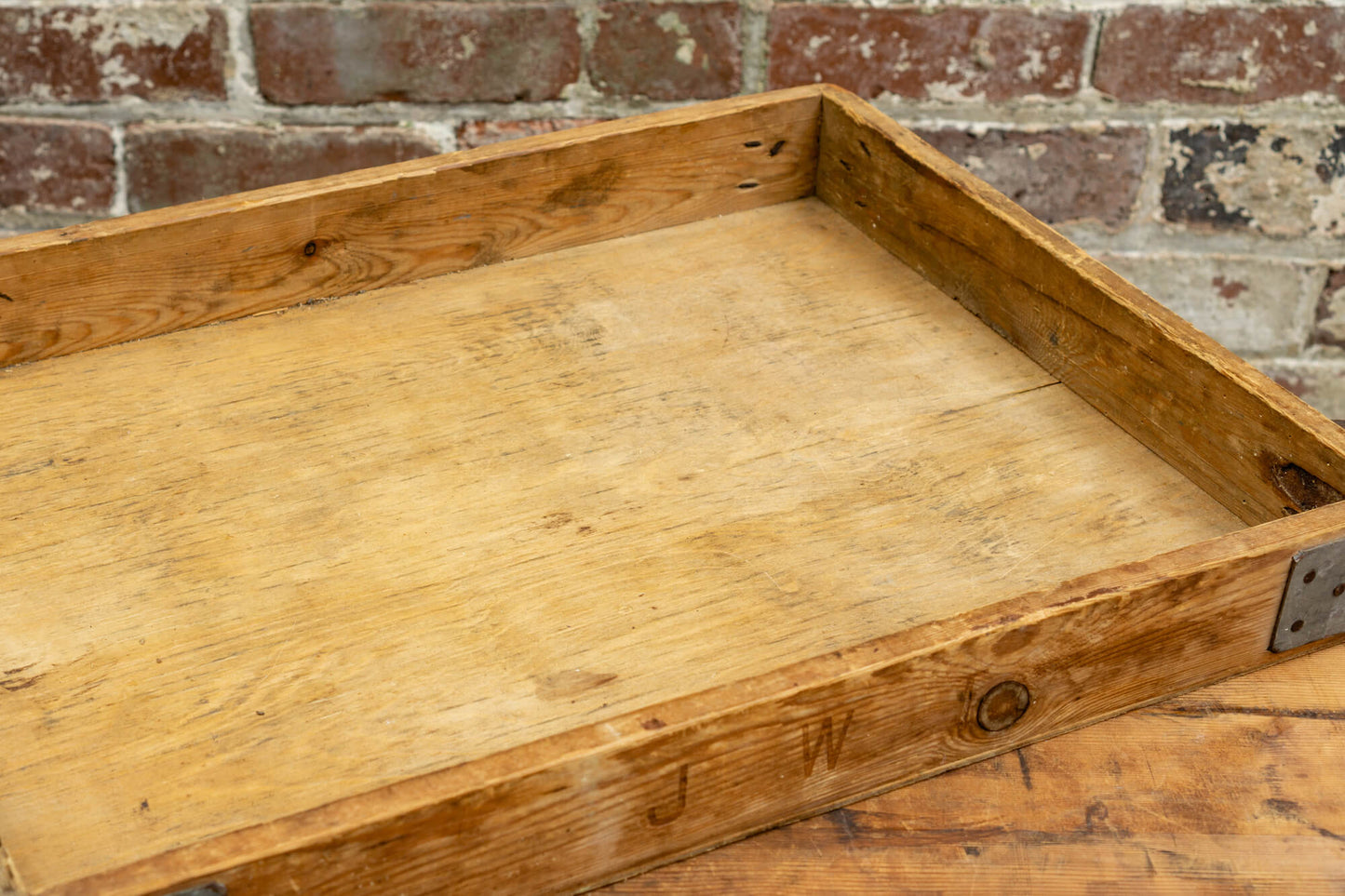 Photo shows a vintage selection of wooden seed trays atop a table. The background is a red rustic brick wall.